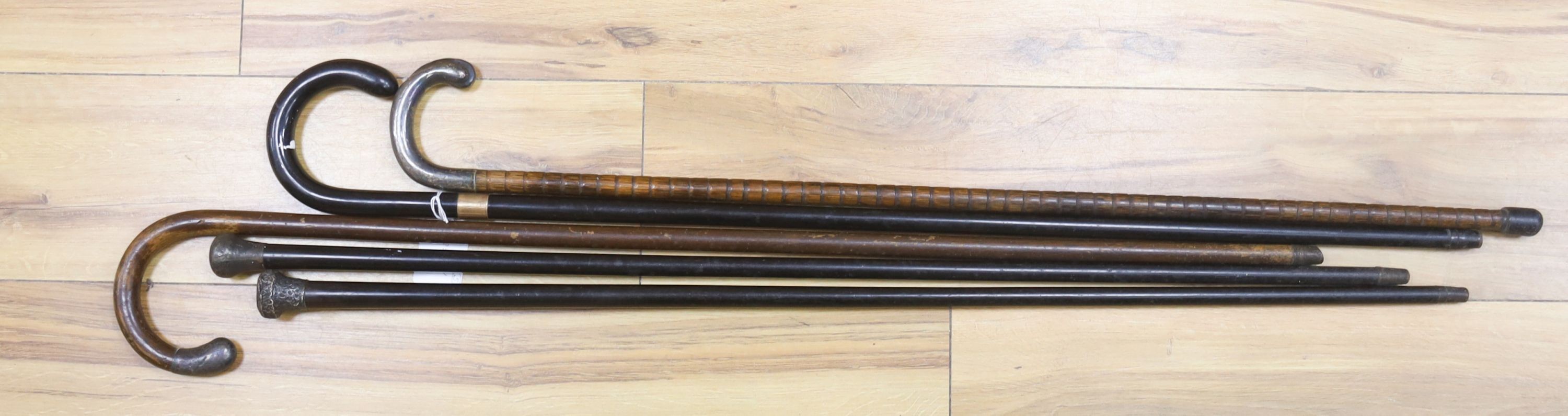A 9ct gold mounted walking stick, three silver-topped sticks and another